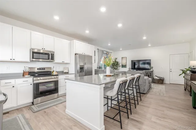 a kitchen with stainless steel appliances a stove a sink a microwave a refrigerator and cabinets