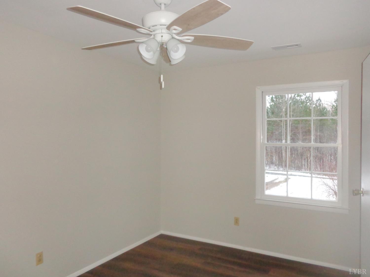1136 Staunton Hill Road Brookneal, VA 24528 - Photo 13 of 22 an empty room with wooden floor fan and windows