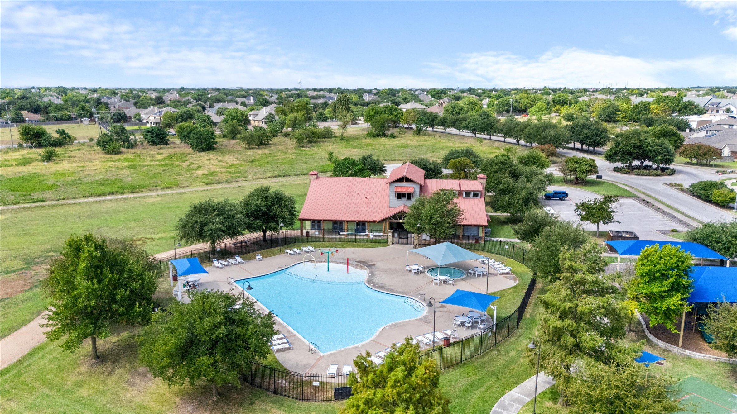 20704 Windmill Ridge Street Pflugerville, TX 78660 - Photo 34 of 34 An inviting community pool and clubhouse awaits, nestled amidst green spaces and residential charm.