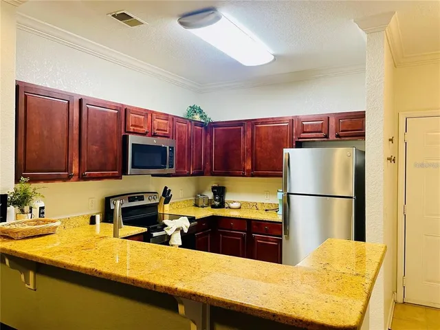 a kitchen with a sink a kitchen island a cabinetry a stove and a refrigerator