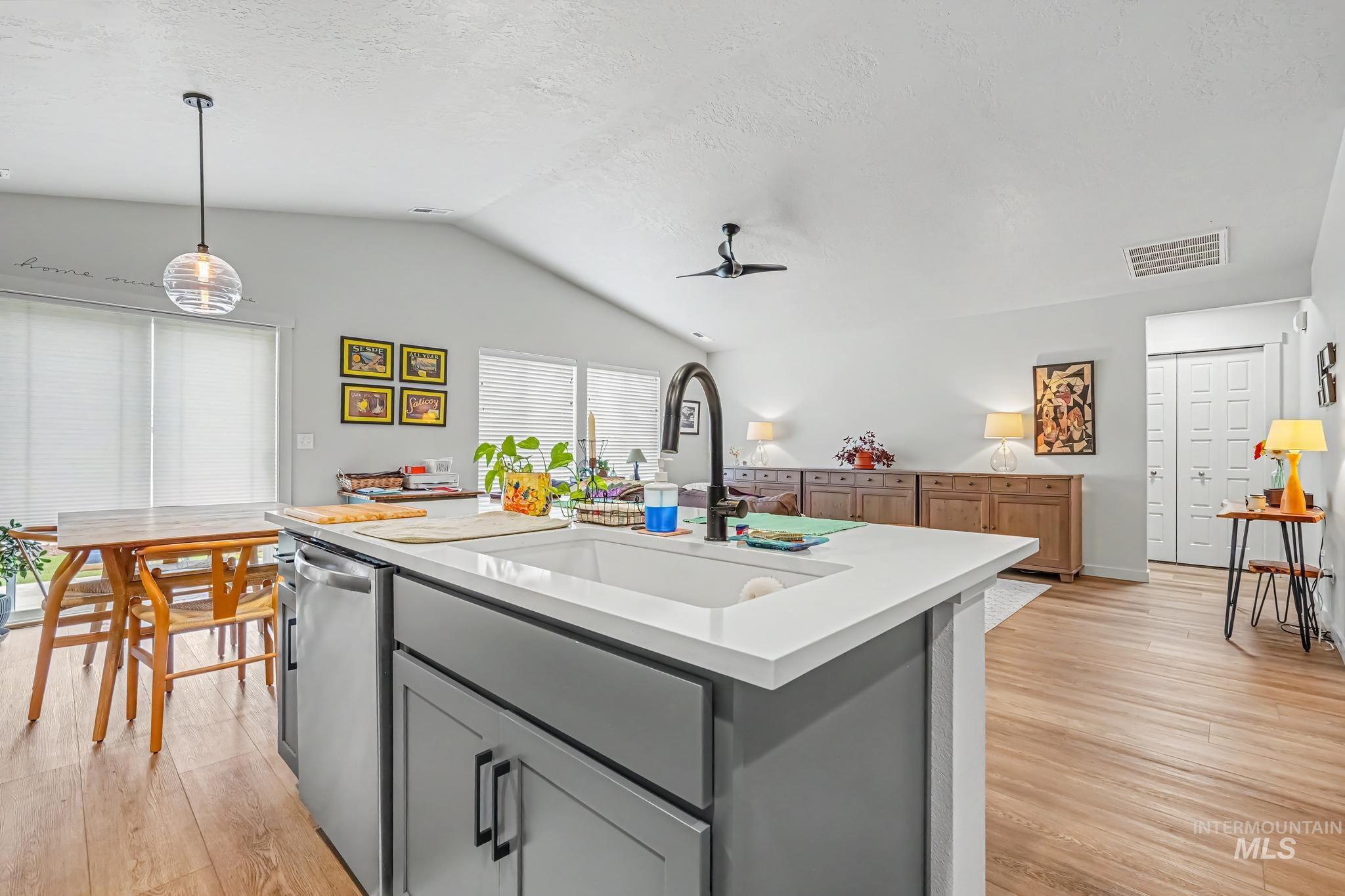 238 West Riggs Spring Avenue Meridian, ID 83642 - Photo 7 of 16 Kitchen island with a built-in sink, stainless steel dishwasher, and gray cabinetry with black hardware