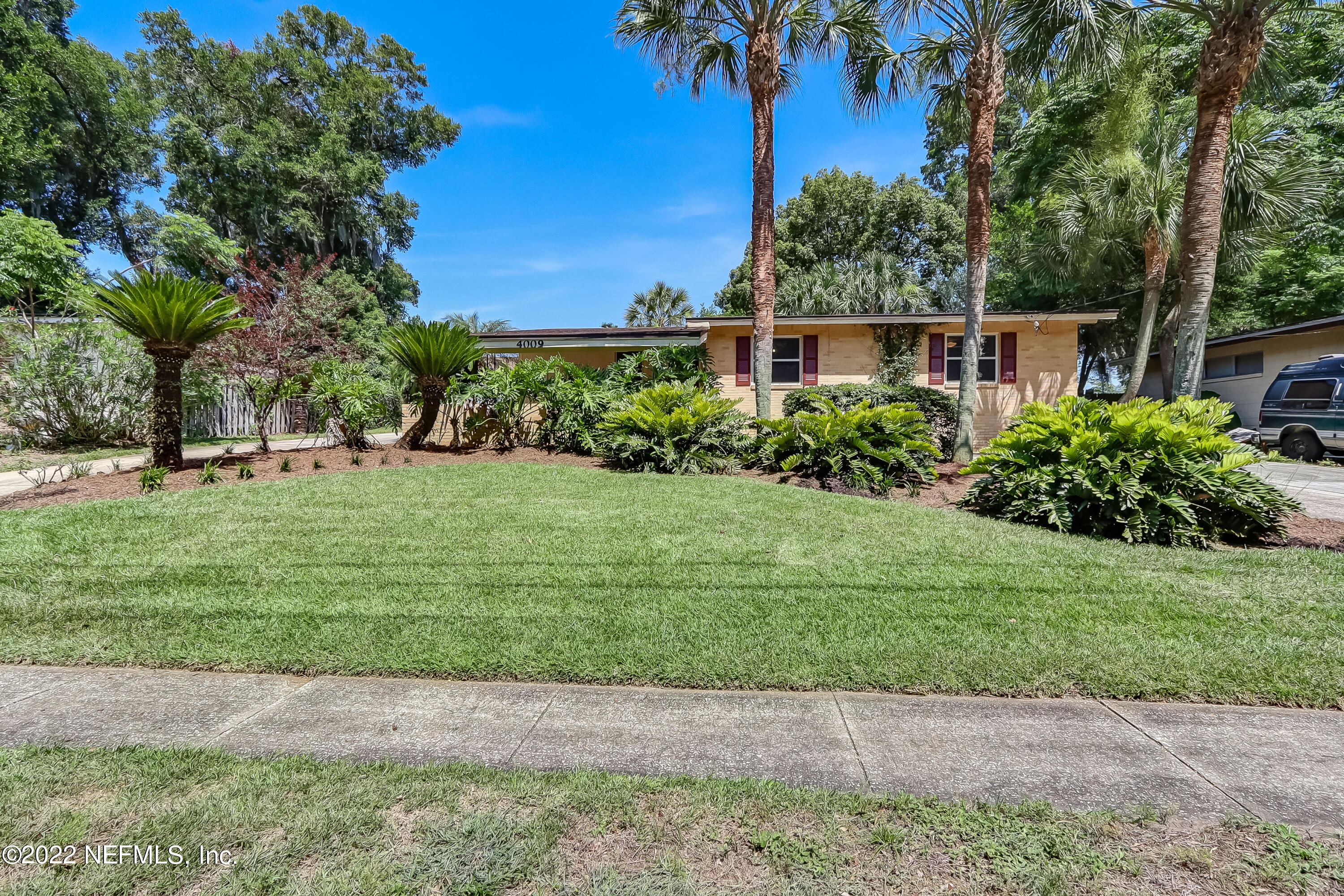 a front view of a house with a yard and potted plants