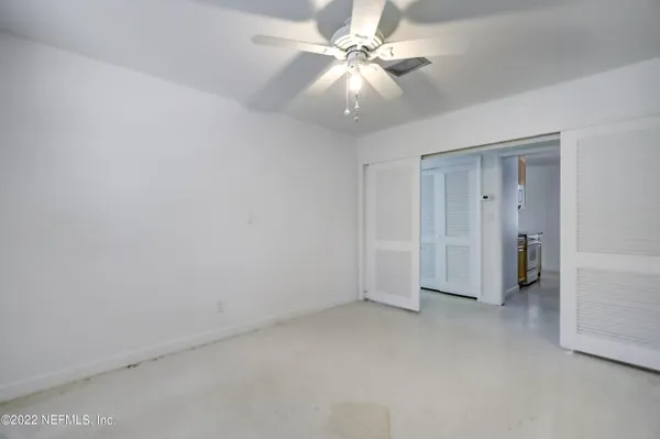 an empty room with windows and fan