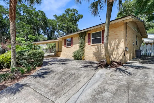 a backyard of a house with table and chairs plants and large trees