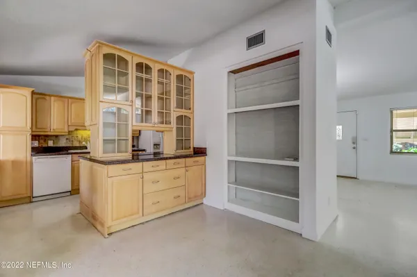 a kitchen with granite countertop a stove and white cabinets