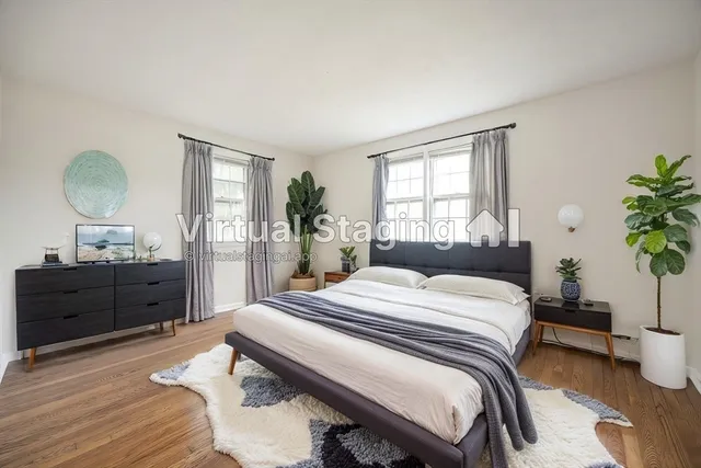 a bedroom with a bed and window with wooden floor