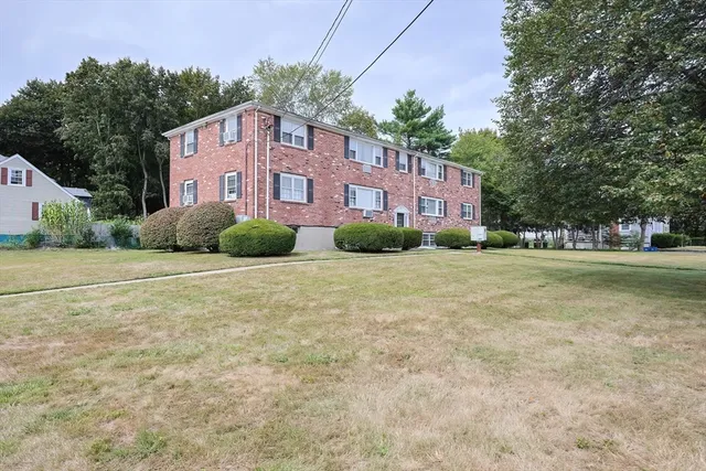 a brick house with a big yard plants and big trees