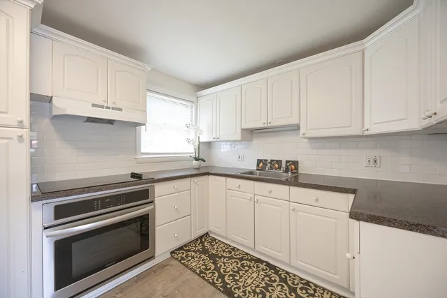 a kitchen with granite countertop white cabinets and stainless steel appliances