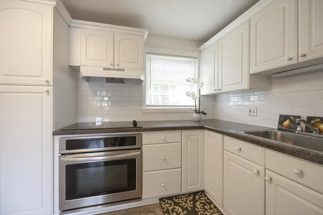 a kitchen with white cabinets and appliances