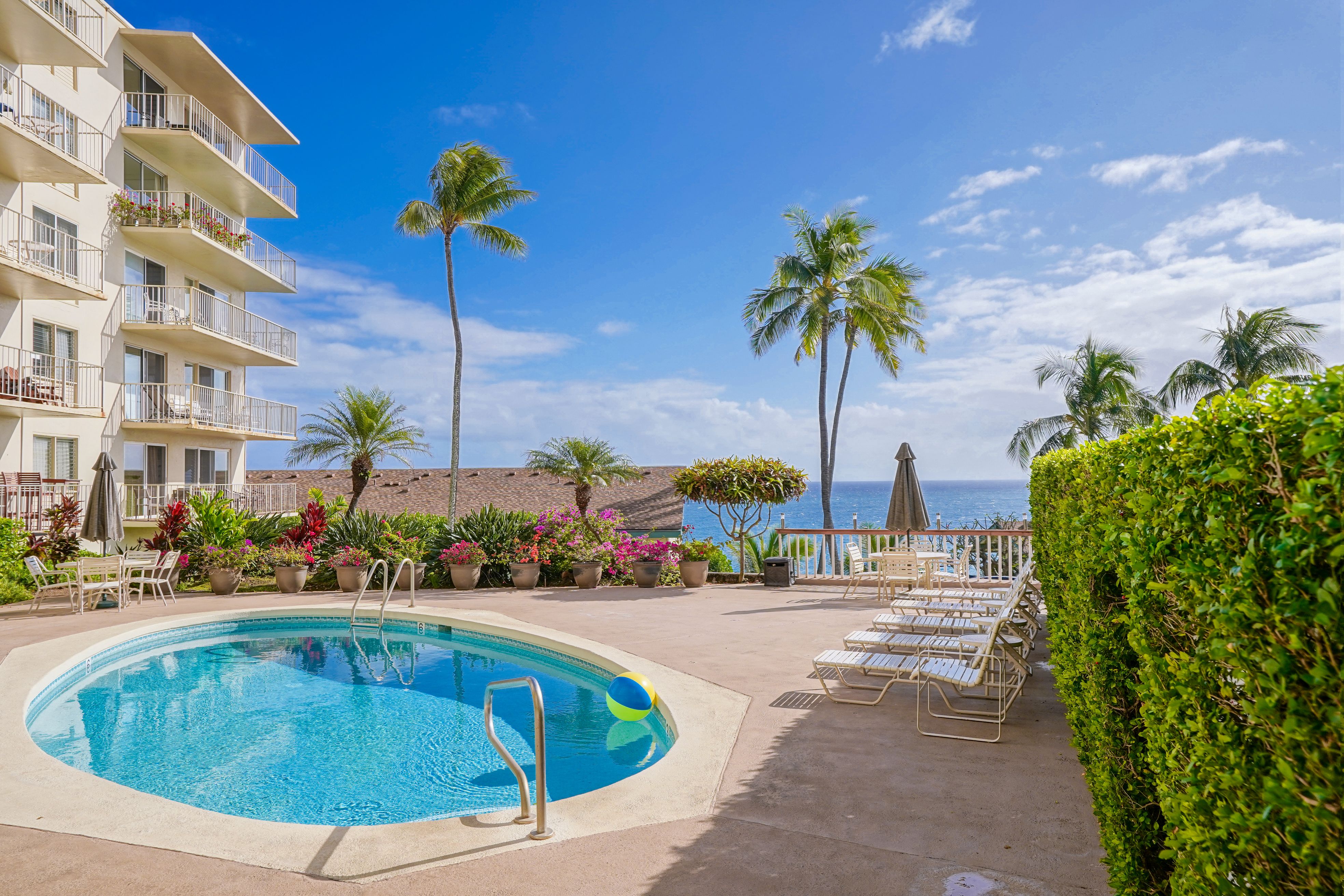 1763 Pe'e Road, Unit 203 Koloa, HI 96756 - Photo 17 of 27 a view of a swimming pool with a table and chairs