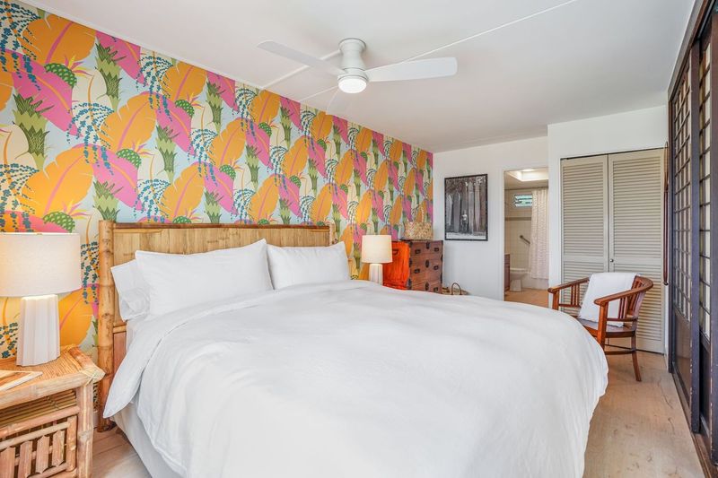 1763 Pe'e Road, Unit 203 Koloa, HI 96756 - Photo 10 of 27 a spacious bedroom with a bed and a painting on the wall