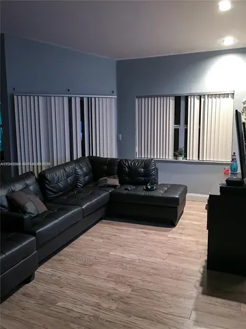 a black leather couch in a living room with wooden floor
