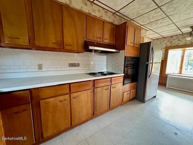 a kitchen with stainless steel appliances granite countertop a sink a refrigerator and cabinets