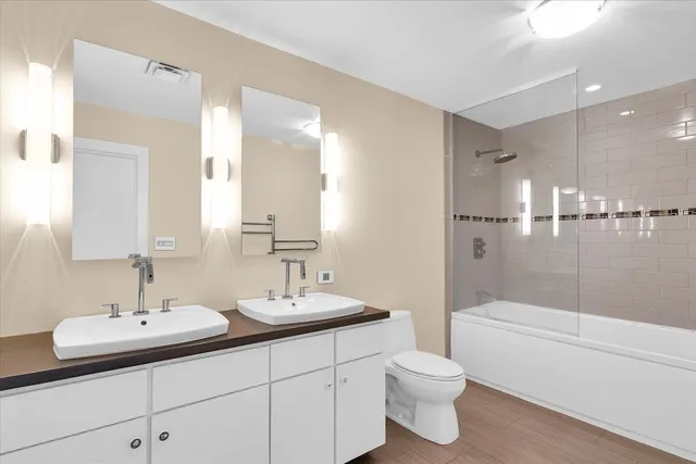 a bathroom with a double vanity sink toilet and shower