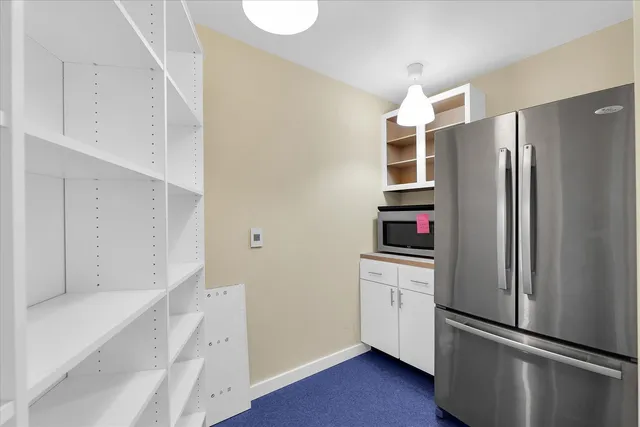 a view of a kitchen counter top space with stainless steel appliances wooden floor and windows
