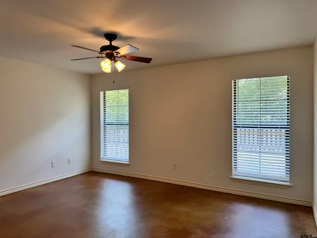 an empty room with windows and chandelier fan