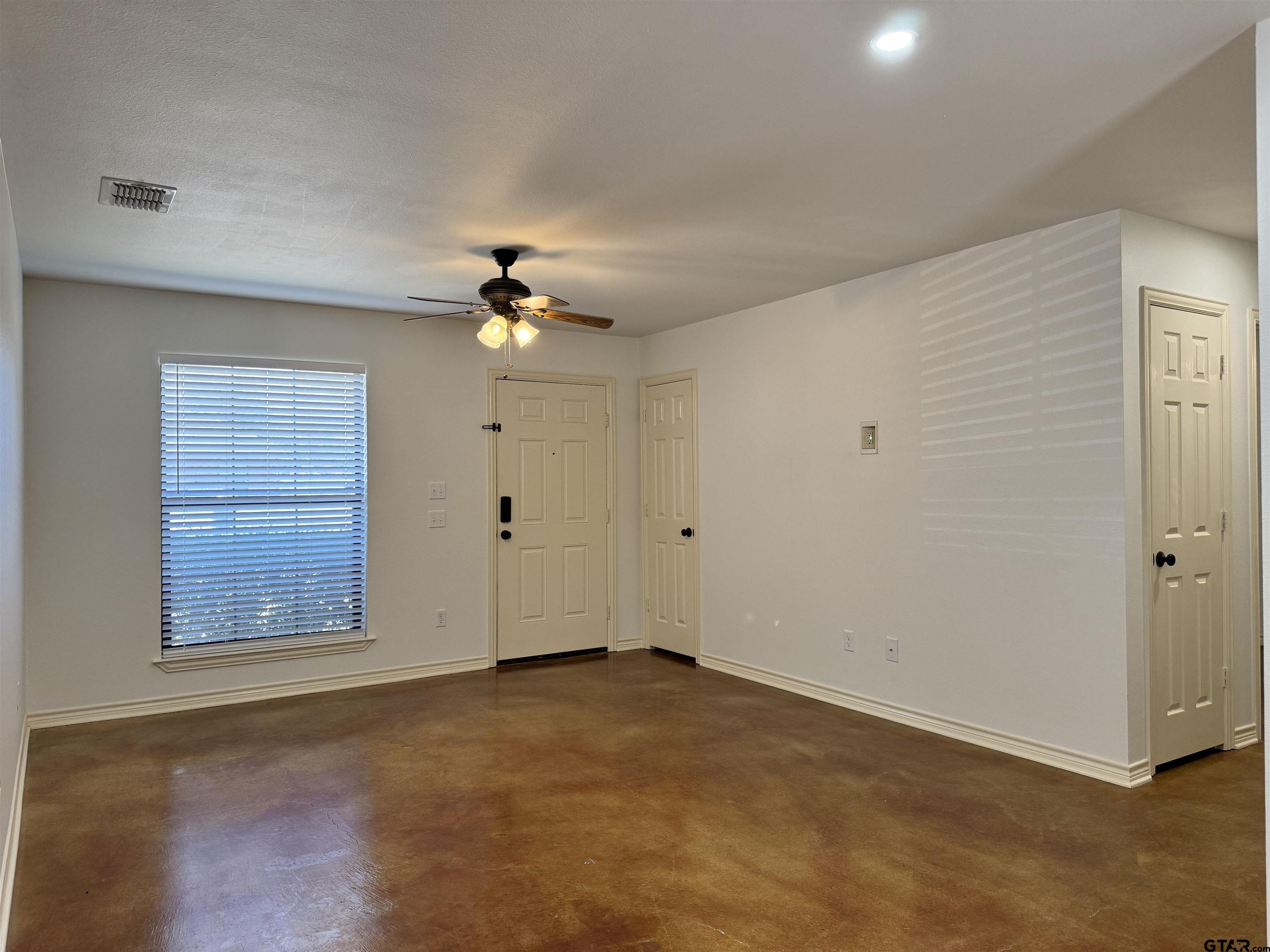 13343 Country Meadow Lane Lindale, TX 75771 - Photo 8 of 20 an empty room with a chandelier fan and windows