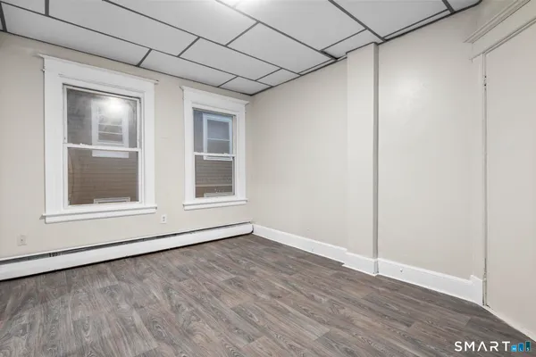 a view of an empty room with wooden floor and a window