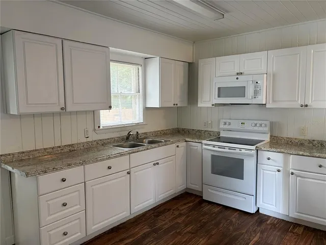 a kitchen with granite countertop white cabinets and white appliances