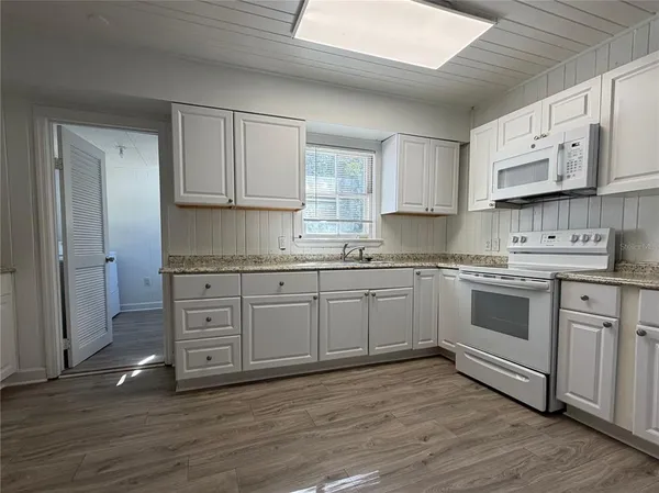 a kitchen with stainless steel appliances granite countertop a stove a sink and white cabinets