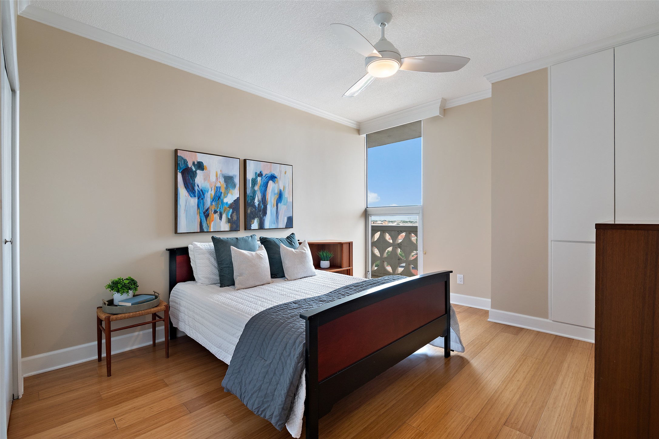 1801 Lavaca Street, Unit 13EF Austin, TX 78701 - Photo 13 of 40 Bedroom featuring ornamental molding, light wood-style floors, a textured ceiling, and a ceiling fan
