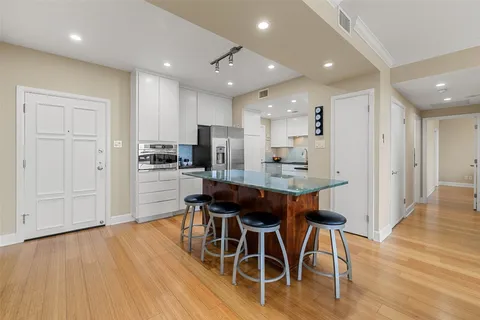 a kitchen with stainless steel appliances kitchen island granite countertop a table chairs and a refrigerator