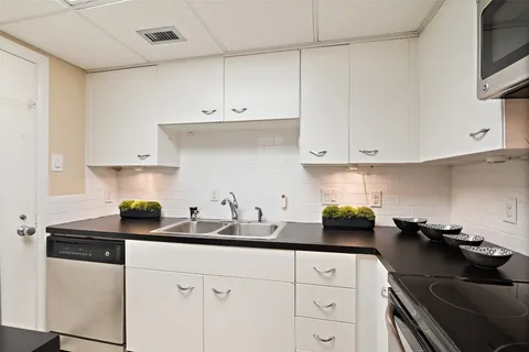 a kitchen with white cabinets a sink and white appliances