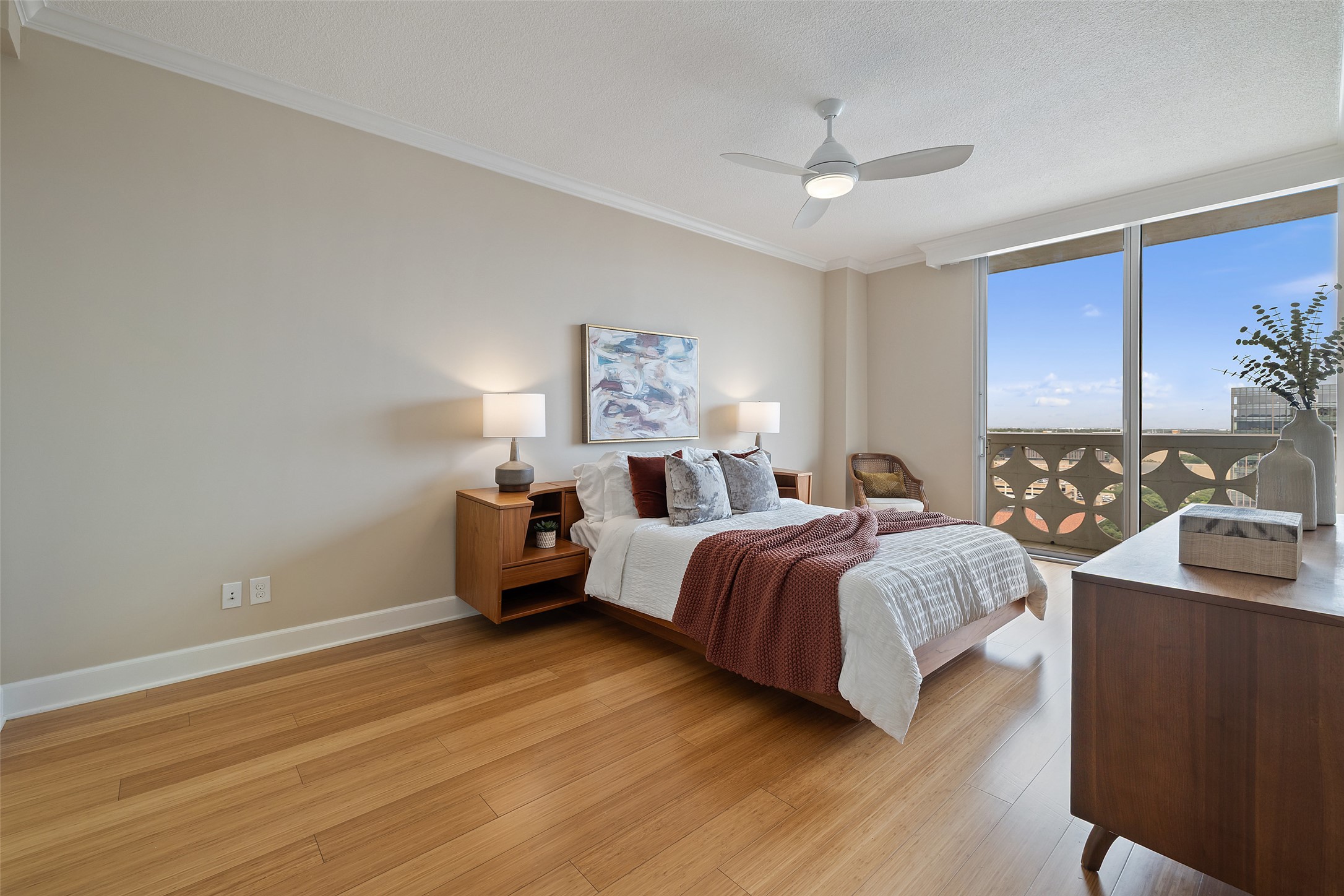 1801 Lavaca Street, Unit 13EF Austin, TX 78701 - Photo 27 of 40 Bedroom featuring light wood finished floors, ornamental molding, a wall of windows, a ceiling fan, and a textured ceiling