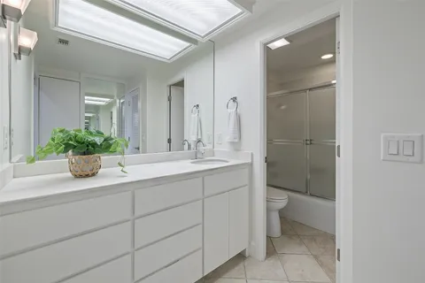 a bathroom with a granite countertop sink a toilet and a mirror