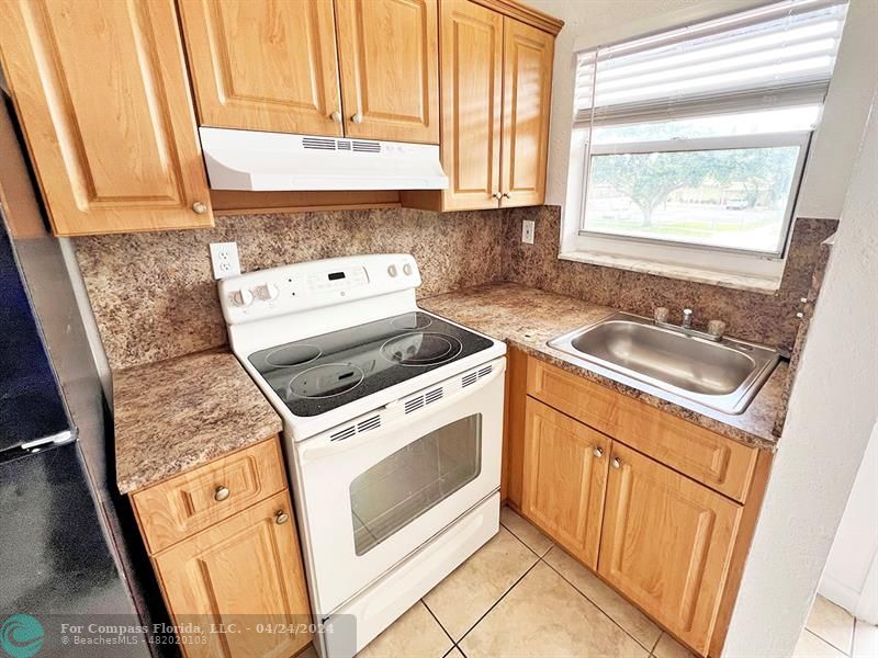 a kitchen with granite countertop white cabinets sink and a stove