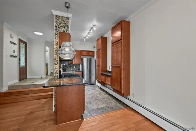 a kitchen with stainless steel appliances granite countertop a refrigerator a stove and a sink with wooden cabinets