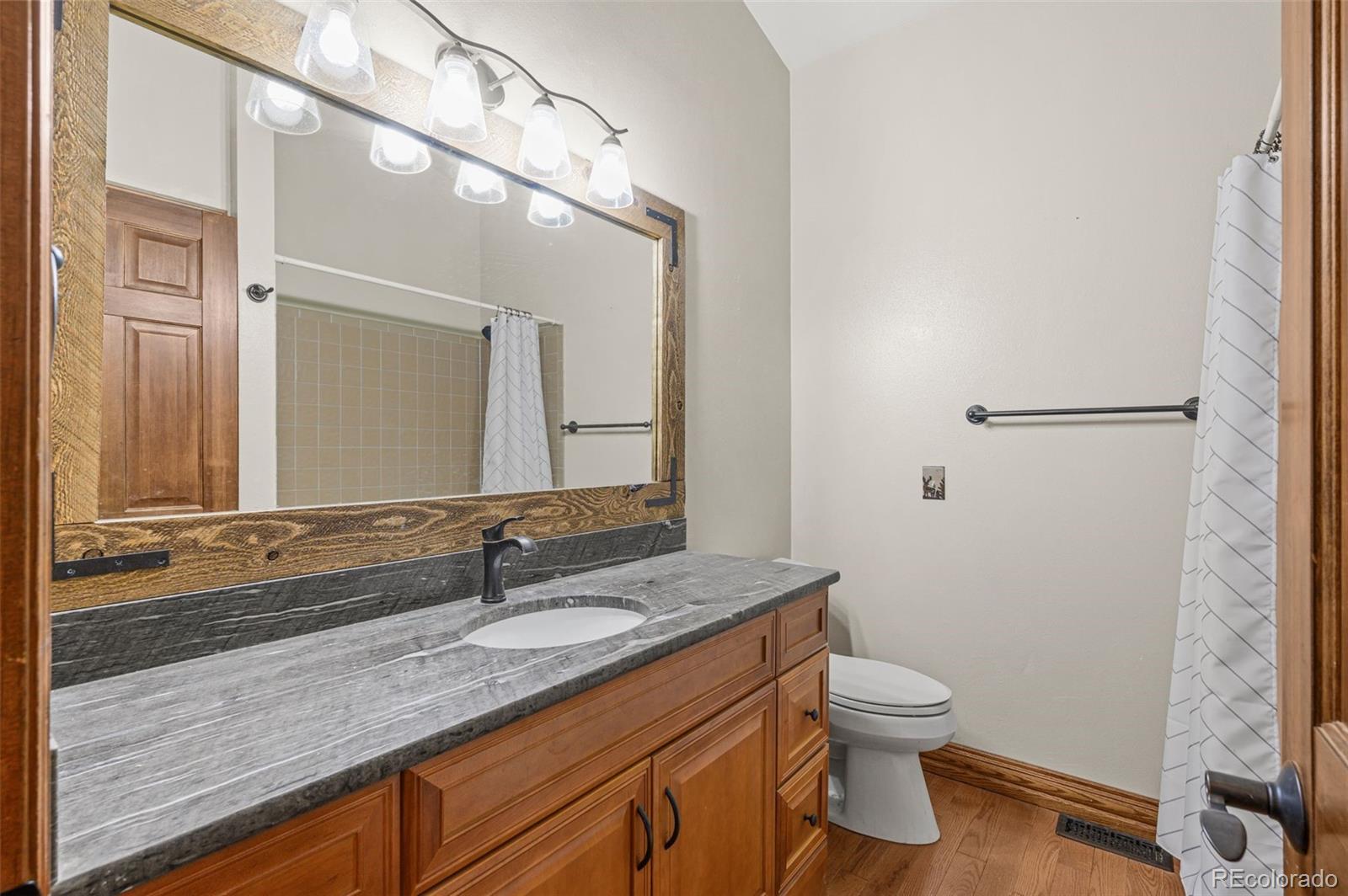 30243 Pine Crest Drive Evergreen, CO 80439 - Photo 19 of 36 a bathroom with a granite countertop sink a toilet and a mirror