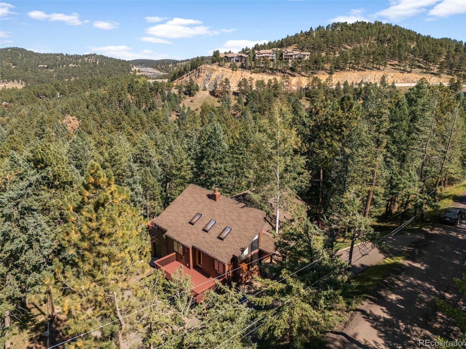 30243 Pine Crest Drive Evergreen, CO 80439 - Photo 2 of 36 an aerial view of a house with a yard and mountain view in back