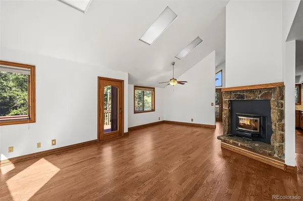 a view of an empty room with wooden floor fireplace and a window