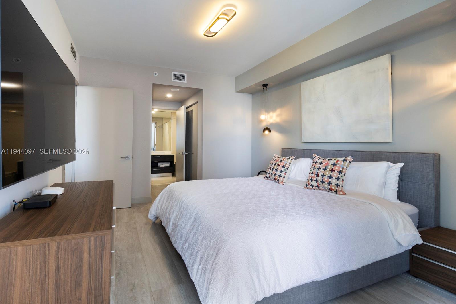 55 Southwest 9th Street, Unit 3010 Miami, FL 33130 - Photo 5 of 15 a bedroom with a bed and a flat tv screen on dresser