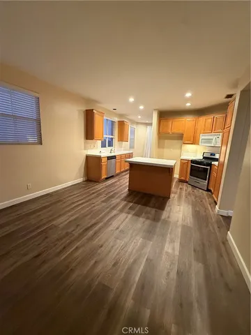 a large white kitchen with wooden floor and a sink