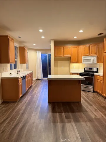 a large room with kitchen island a sink wooden floor and a view of living room