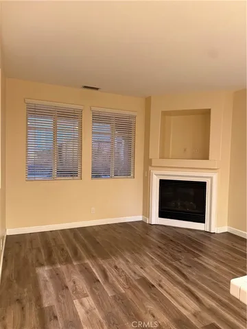 a view of empty room with wooden floor and fireplace