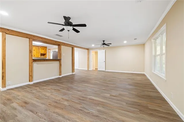 a view of empty room with wooden floor and fan
