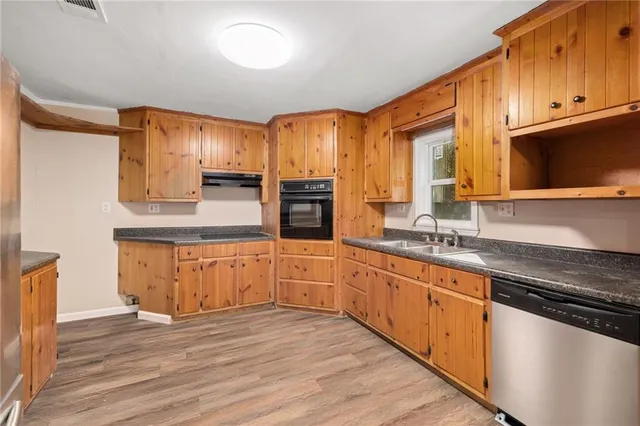 a large kitchen with granite countertop a sink counter space stainless steel appliances and cabinets