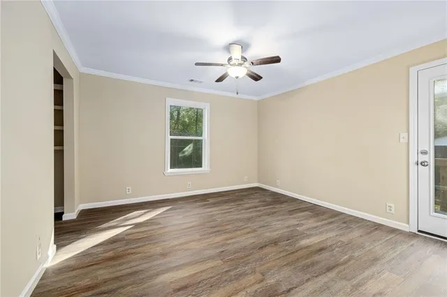 a view of an empty room with wooden floor and a window