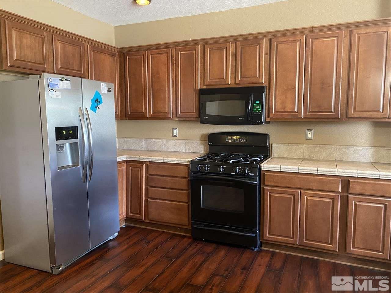 11034 Colton Drive Reno, NV 89521 - Photo 5 of 13 a kitchen with granite countertop a refrigerator stove and microwave