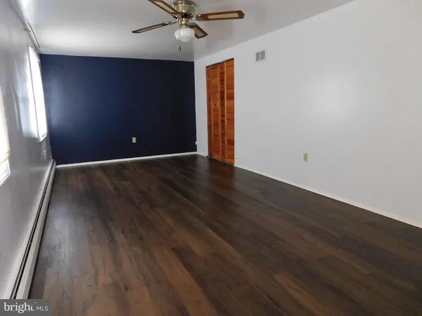 an empty room with wooden floor fan and windows