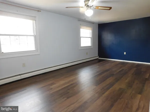 an empty room with wooden floor fan and windows