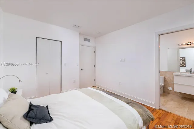 a bedroom with a bed and a potted plant on the dresser