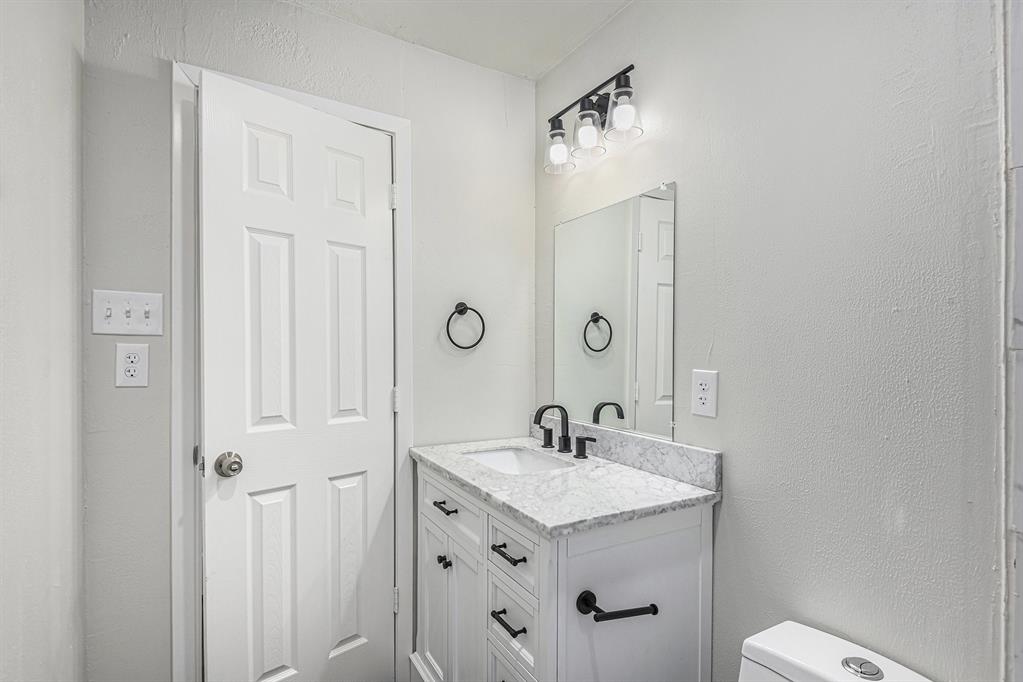 233 Victoria Avenue Azle, TX 76020 - Photo 18 of 25 Half bath featuring a textured wall and vanity
