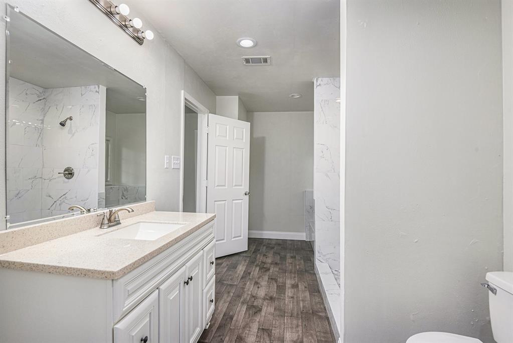 233 Victoria Avenue Azle, TX 76020 - Photo 22 of 25 Bathroom with vanity, a marble finish shower, and dark wood-style floors