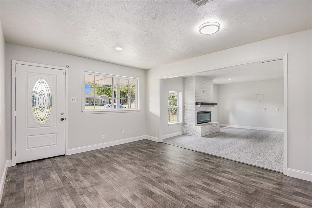 233 Victoria Avenue Azle, TX 76020 - Photo 6 of 25 Entrance foyer with a textured ceiling, dark wood-style flooring, a brick fireplace, and recessed lighting