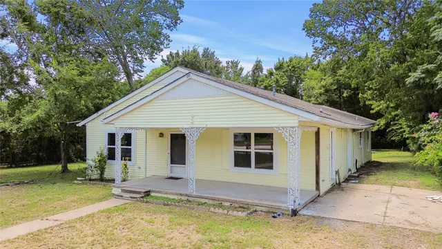 a view of a house with a yard potted plants and a large tree