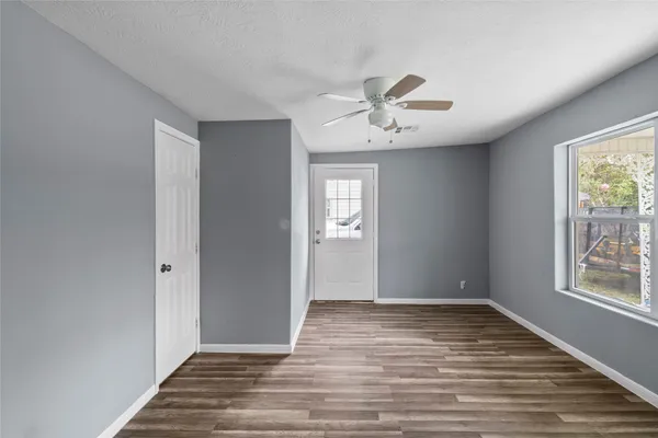 a view of an empty room with wooden floor and a window